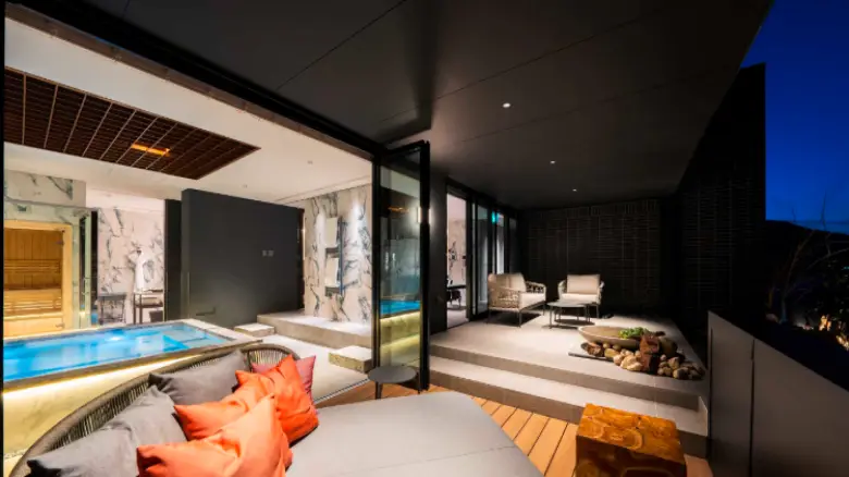 ラグジュアリーな屋外テラスと室内温泉が見える高級旅館の客室の風景。リラックスできる家具と現代的なデザインが印象的。