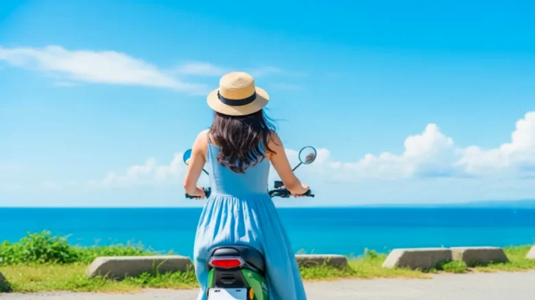 海を望む糸島の道を電動スクーターで走る女性の後ろ姿